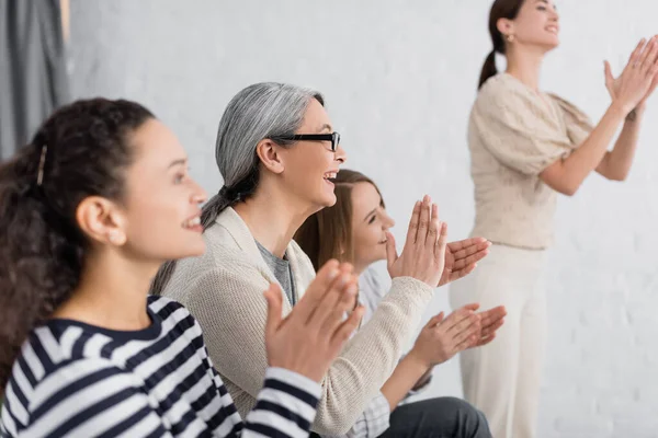 Heureux asiatique femme d'affaires dans lunettes applaudissant près de groupe de femmes pendant séminaire — Photo de stock