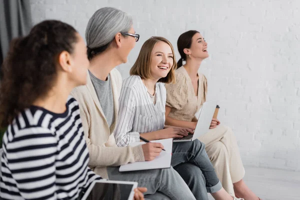 Donne d'affari multiculturali sorridenti mentre tengono gadget durante il seminario — Foto stock