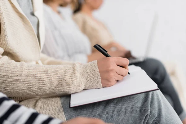 Visión parcial de la mujer de negocios escribiendo en cuaderno durante el seminario - foto de stock