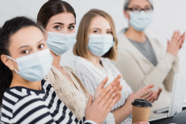 Empresarias multiculturales en máscaras médicas aplaudiendo durante el seminario - foto de stock