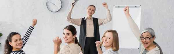 Happy interracial businesswomen and speaker with raised hands during lecture, banner — Stock Photo