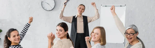 Mujeres de negocios interracial feliz y orador con las manos levantadas durante la conferencia, pancarta - foto de stock