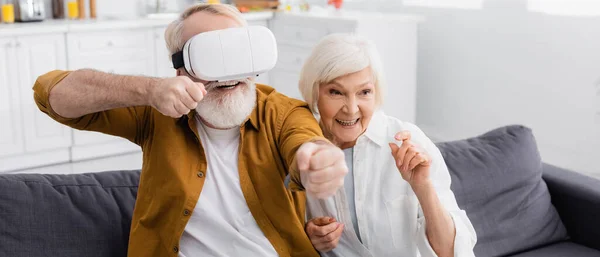 Lächelnde Seniorin sitzt neben Ehemann in vr auf Couch, Banner — Stockfoto