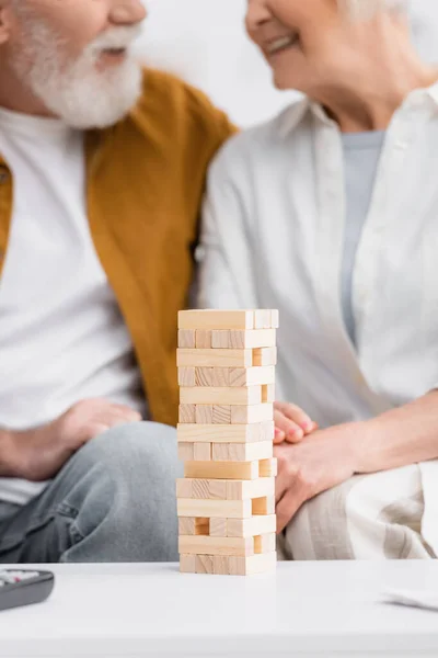 Vista cortada de blocos de jogo de torre de madeira perto casal sênior no fundo borrado — Fotografia de Stock