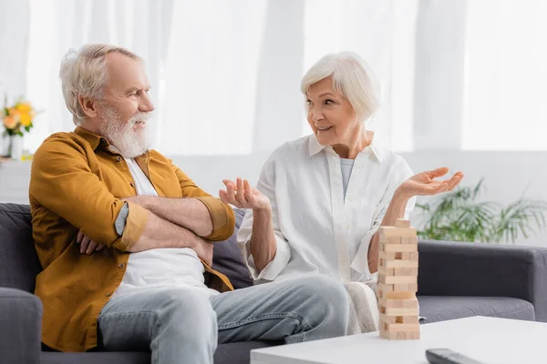 Senior woman talking with husband near blocks wood game on blurred foreground — Stock Photo