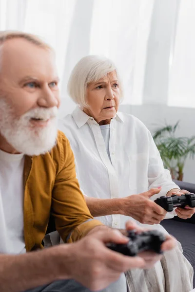 KYIV, UKRAINE - DECEMBER 17, 2020: Sad senior woman with joystick sitting near husband on blurred foreground — Stock Photo