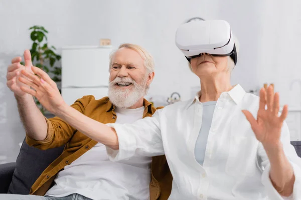 Senior woman using vr headset near cheerful husband — Stock Photo