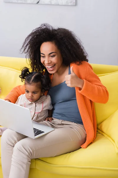 Feliz afro-americana mãe mostrando polegar para cima durante chamada de vídeo perto da filha da criança — Fotografia de Stock