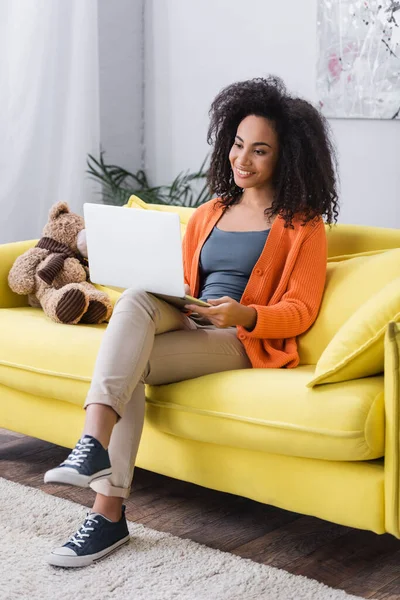 Complacido freelancer afroamericano usando laptop en casa - foto de stock