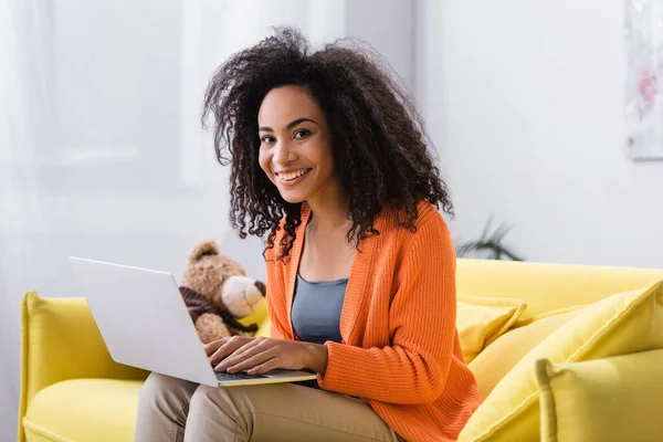 Cheerful young african american freelancer using laptop at home — Stock Photo
