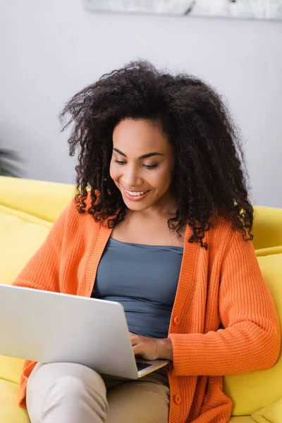 Freelancer afro-americano positivo usando laptop em casa — Fotografia de Stock