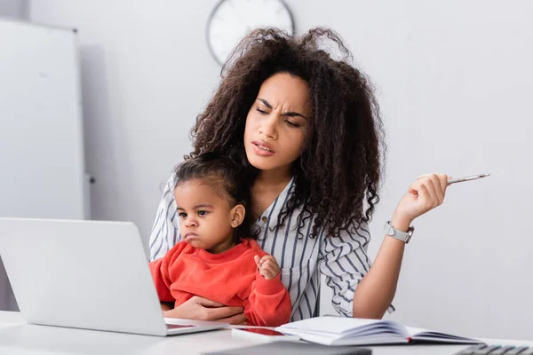 Afrikanisch-amerikanische Mutter sitzt mit Kleinkind Tochter und schaut auf Laptop auf Schreibtisch — Stockfoto
