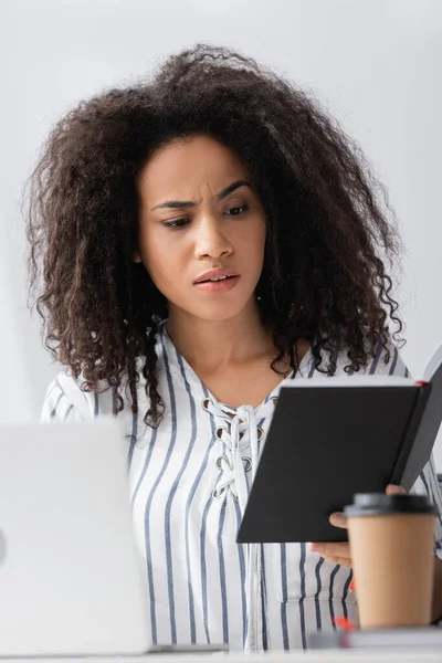 Afrikanisch-amerikanischer Freiberufler schaut von zu Hause aus auf das Notizbuch — Stockfoto