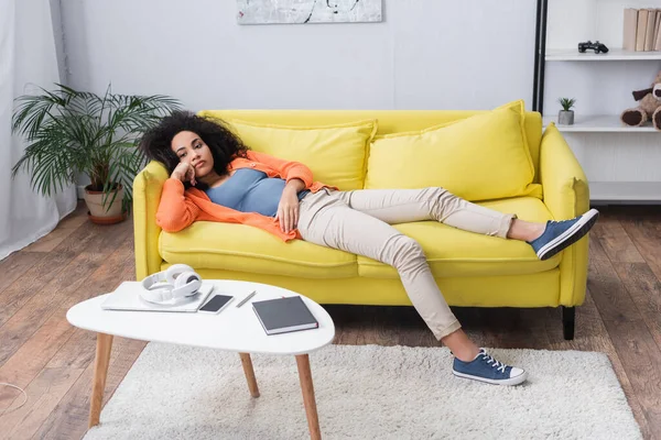 Annoiato africano americano donna agghiacciante su divano giallo — Foto stock