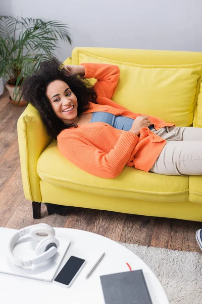 Fröhliche afrikanisch-amerikanische Frau chillt auf gelber Couch — Stockfoto