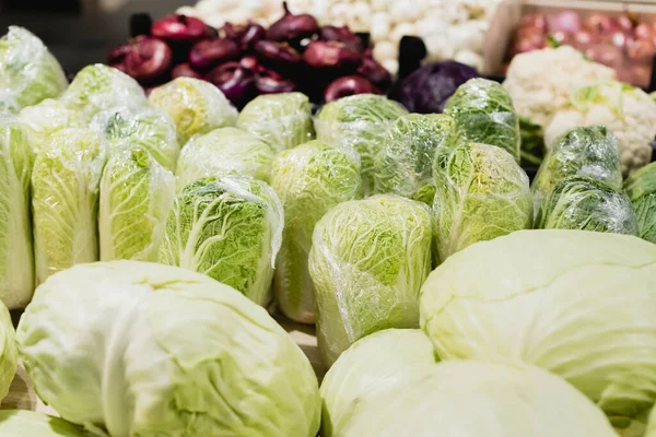 Close up view of fresh cabbages near vegetables on blurred background in supermarket — Stock Photo