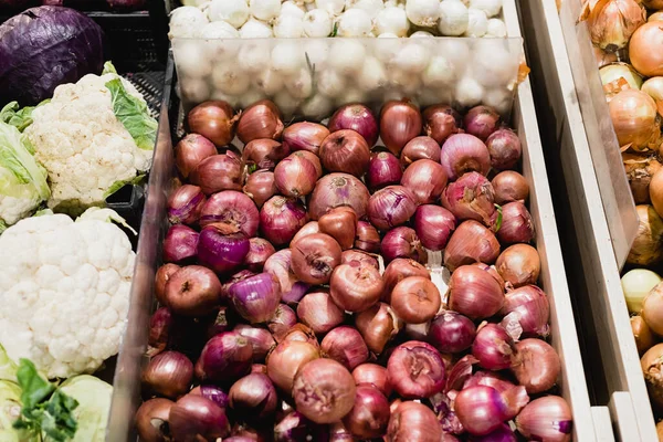 Vista de ángulo alto de cebollas y coliflores en el supermercado - foto de stock