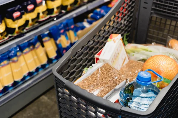 Paquet avec sarrasin et bouteille d'eau dans le panier au supermarché — Photo de stock