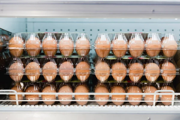 Huevos en envases transparentes en estantería en el supermercado - foto de stock
