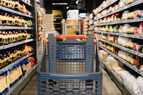 Einkaufswagen in der Nähe von Lebensmitteln im Supermarkt auf verschwommenem Hintergrund — Stockfoto