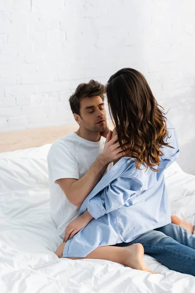 Man hugging seductive woman in blue shirt in bedroom — Stock Photo