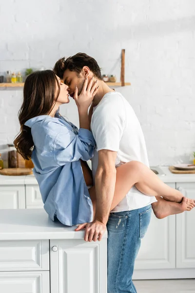 Vista lateral do casal fazendo amor na mesa da cozinha — Fotografia de Stock