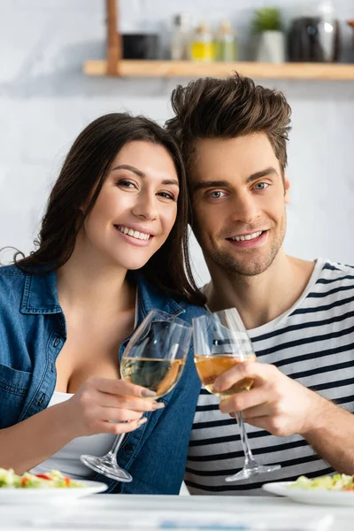 Casal alegre brindar copos de vinho na cozinha — Fotografia de Stock