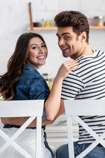 Fröhliche Männer und Frauen, die sich umarmen und auf Stühlen sitzen — Stockfoto