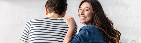 Femme gaie regardant la caméra tout en touchant l'épaule du petit ami, bannière — Photo de stock