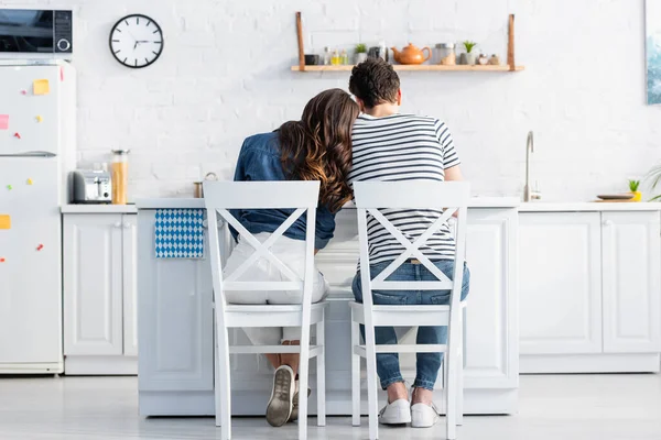 Back view of man and woman sitting on chairs in kitchen — Stock Photo