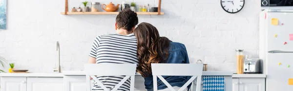 Вид ззаду чоловіка і жінки, що сидить на стільцях на кухні, банер — стокове фото