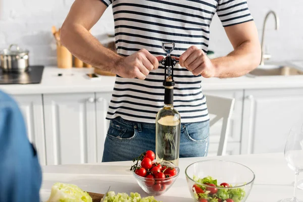 Partial view of man opening bottle of wine in kitchen — Stock Photo