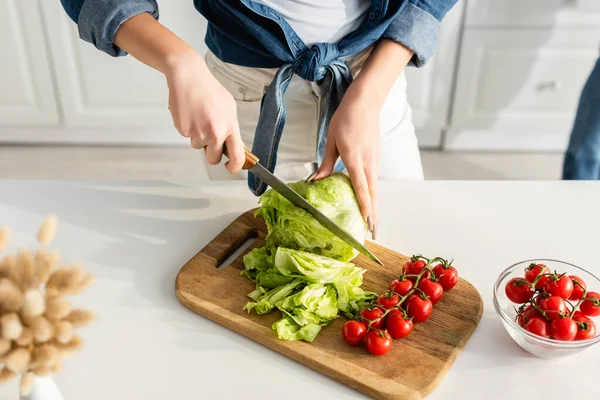 Vista recortada de la lechuga de corte mujer en la tabla de cortar - foto de stock