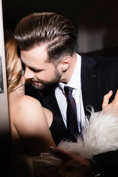 Man in formal wear biting dress of girlfriend in hotel during night — Stock Photo