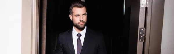 Bearded man in suit looking away in hotel, banner — Stock Photo