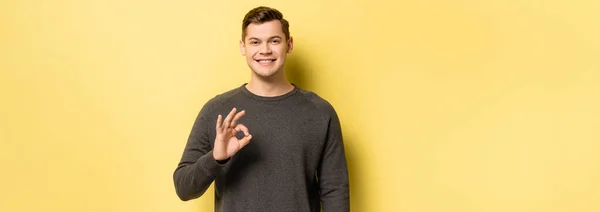 Sorrindo homem mostrando ok sinal no fundo amarelo, banner — Fotografia de Stock