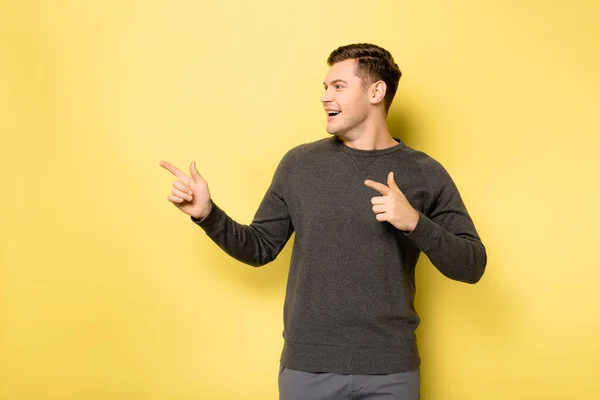 Hombre sonriente señalando con los dedos sobre fondo amarillo - foto de stock