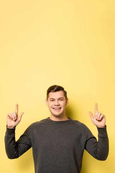 Man pointing with fingers and smiling at camera on yellow background — Stock Photo