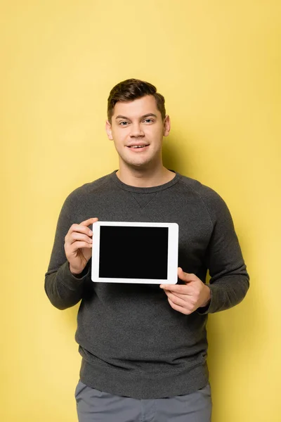 Homem sorridente segurando tablet digital com tela em branco no fundo amarelo — Fotografia de Stock