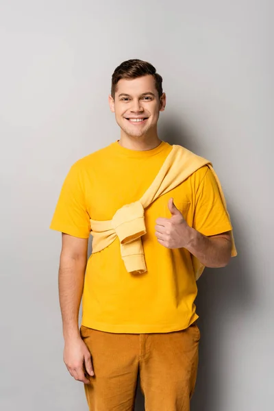 Cheerful man showing like while looking at camera on grey background — Stock Photo