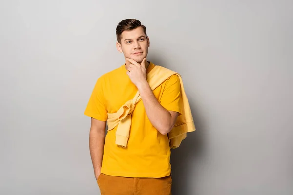 Hombre de ensueño con la mano en el bolsillo sobre fondo gris - foto de stock