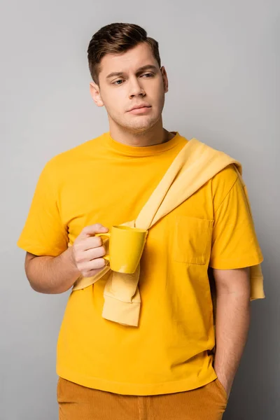 Sad man with yellow cup looking away on grey background — Stock Photo