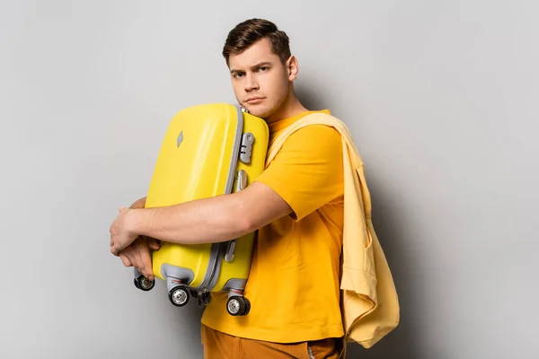 Upset traveler hugging suitcase on grey background — Stock Photo