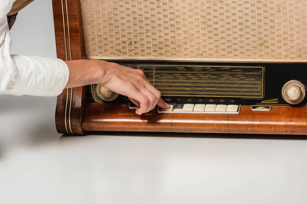 Vue recadrée de la femme appuyant sur le bouton sur le récepteur de radio vintage sur gris — Photo de stock
