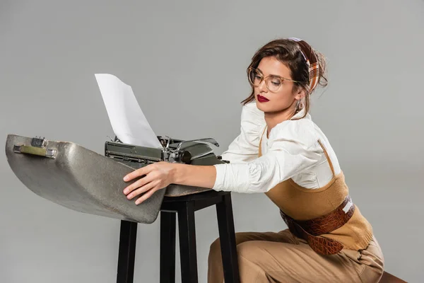 Stylish secretary opening case of vintage typewriter isolated on grey — Stock Photo