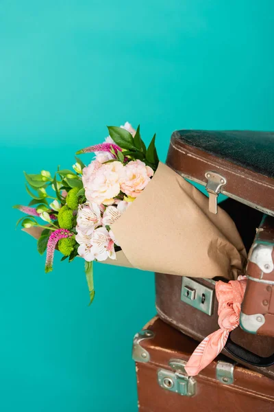 Bouquet of fresh flowers and vintage suitcases isolated on turquoise — Stock Photo