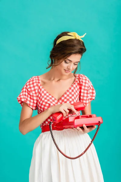 Mujer joven en ropa retro con estilo llamando a teléfono vintage aislado en turquesa - foto de stock