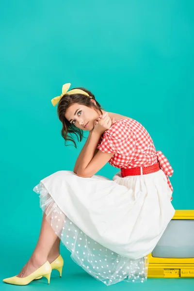 Trendy pin up woman sitting on yellow retro tv and looking at camera on turquoise — Stock Photo