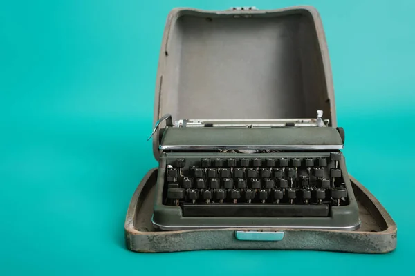 Máquina de escribir retro en estuche abierto sobre fondo turquesa - foto de stock