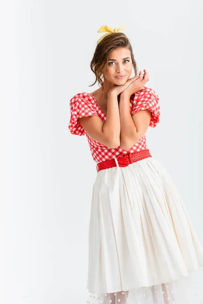 Feliz pin up mujer cogida de la mano cerca de la cara mientras mira a la cámara aislada en blanco - foto de stock